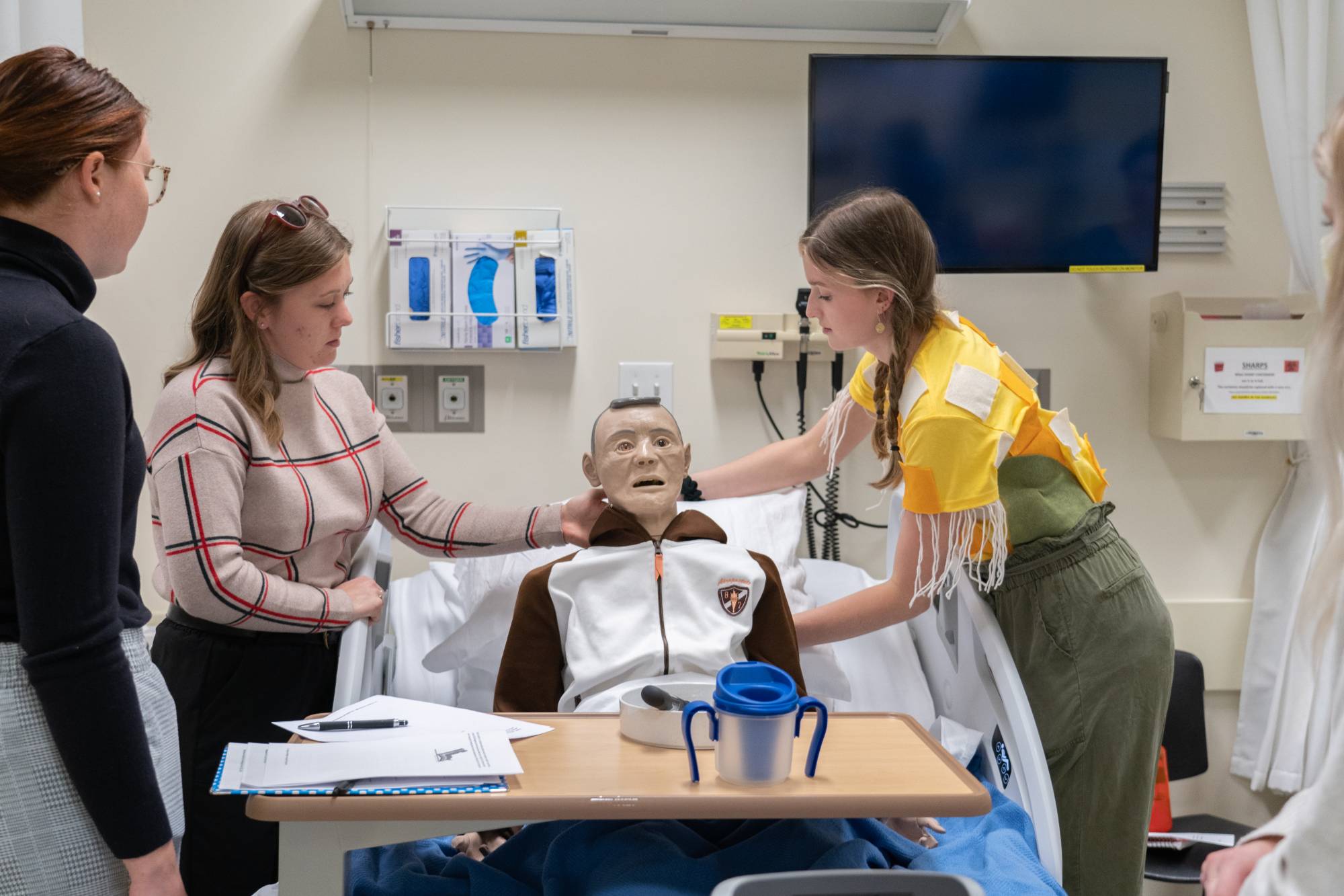 Interprofessional team discussing on optimal positioning strategies with the help of manikin on a hospital bed